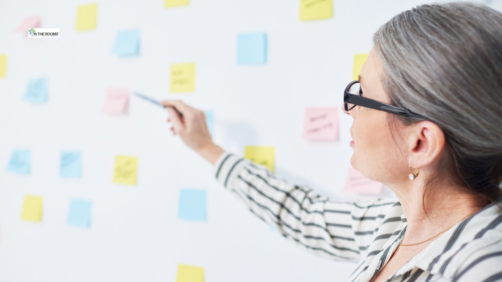 Woman pointing at sticky notes on a wall, representing planning ahead for triggers in recovery.