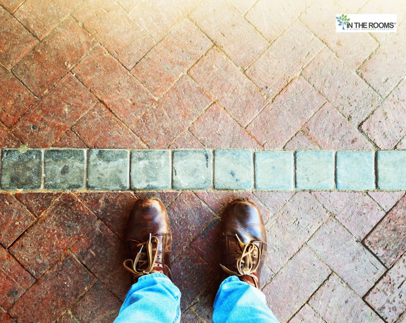 A person standing at a clear line on a brick walkway, symbolizing personal boundaries, limits, and intentional choices in recovery.