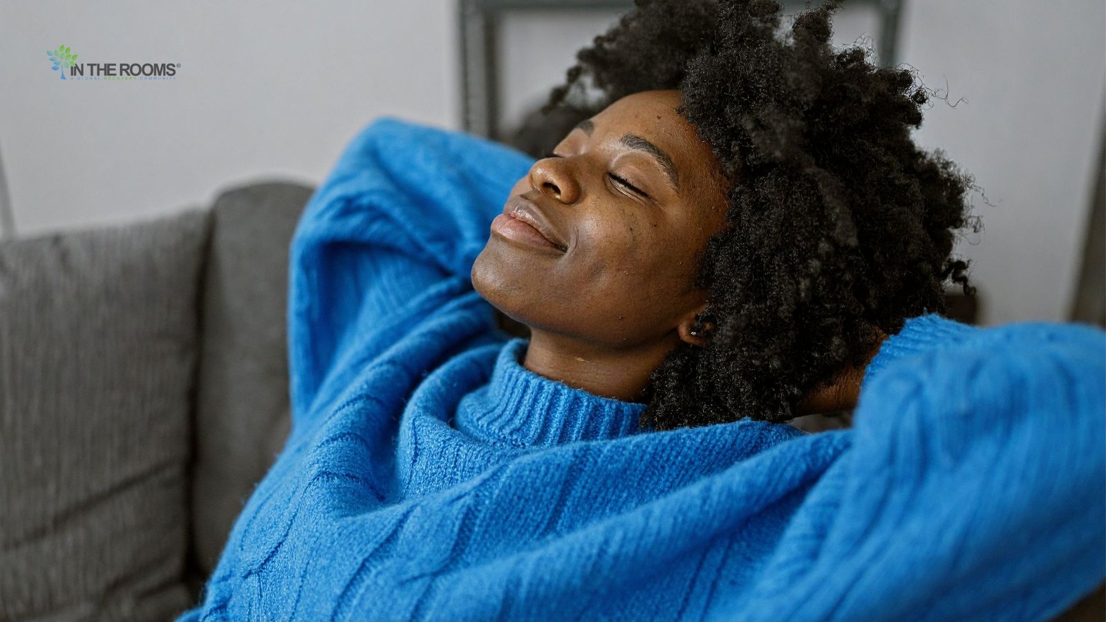 A woman rests peacefully on a couch with her eyes closed, reflecting a sense of calm, comfort, and emotional safety.