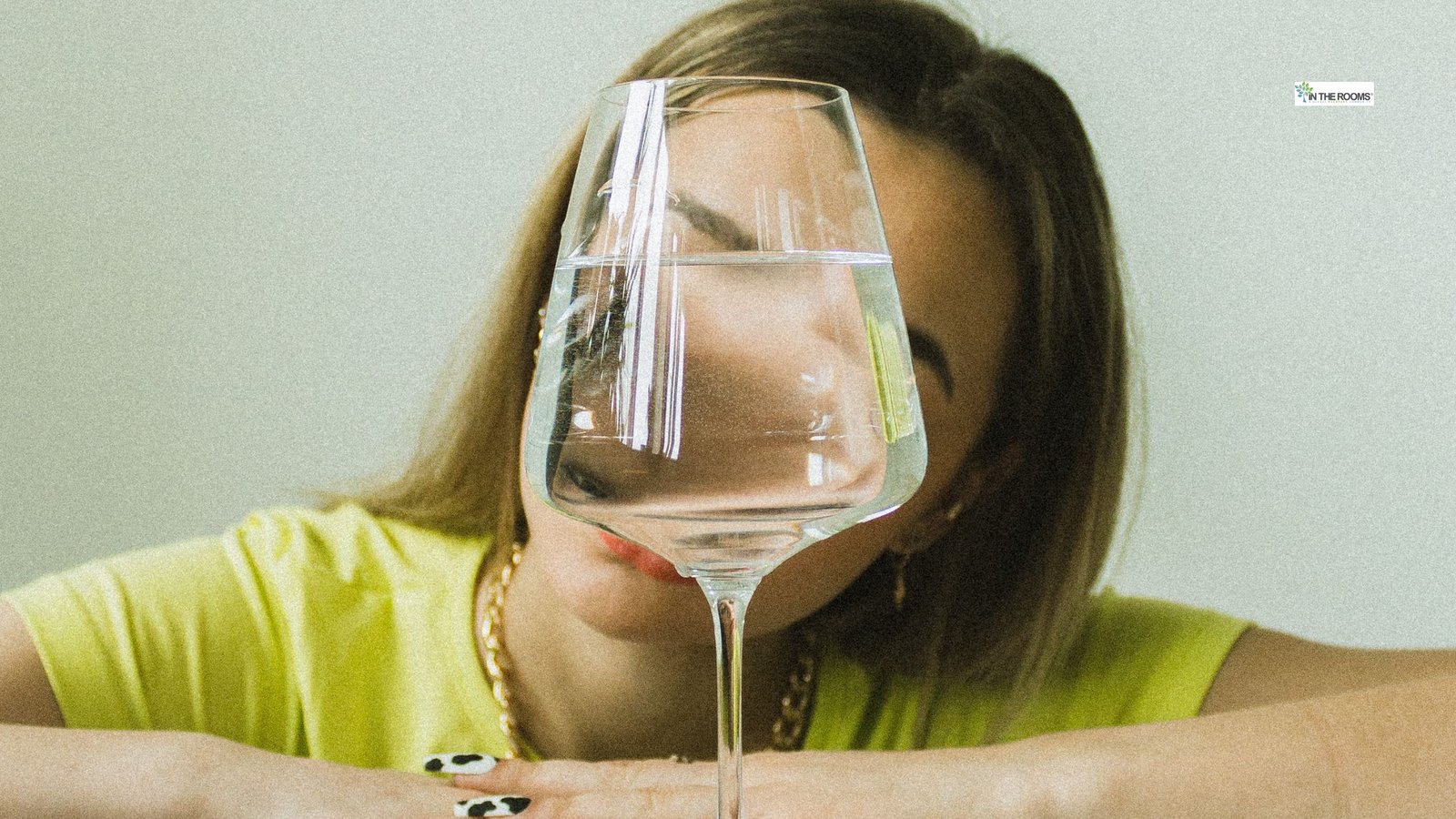 Woman looking at a wine glass placed in front of her during early sobriety.