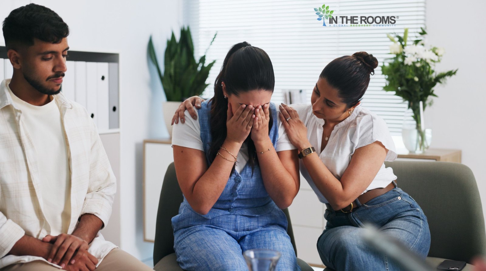 A person receives comfort and support from others during a recovery support group meeting, reflecting healing, connection, and emotional growth in sobriety.