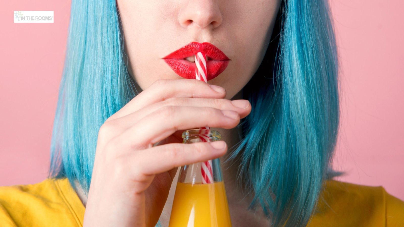 Close-up of a person with bright makeup sipping a drink through a straw, representing the glamorized image of alcohol.