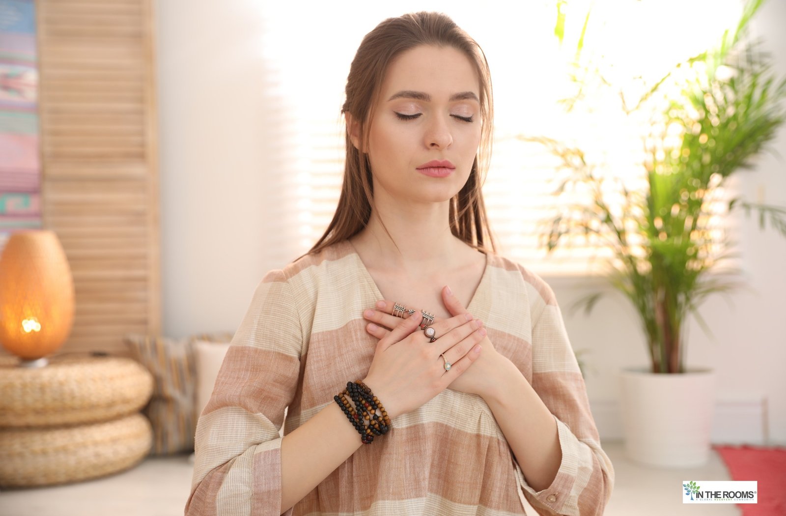 A woman with eyes closed and hands resting on her chest, practicing self-compassion and emotional healing in a peaceful indoor space.