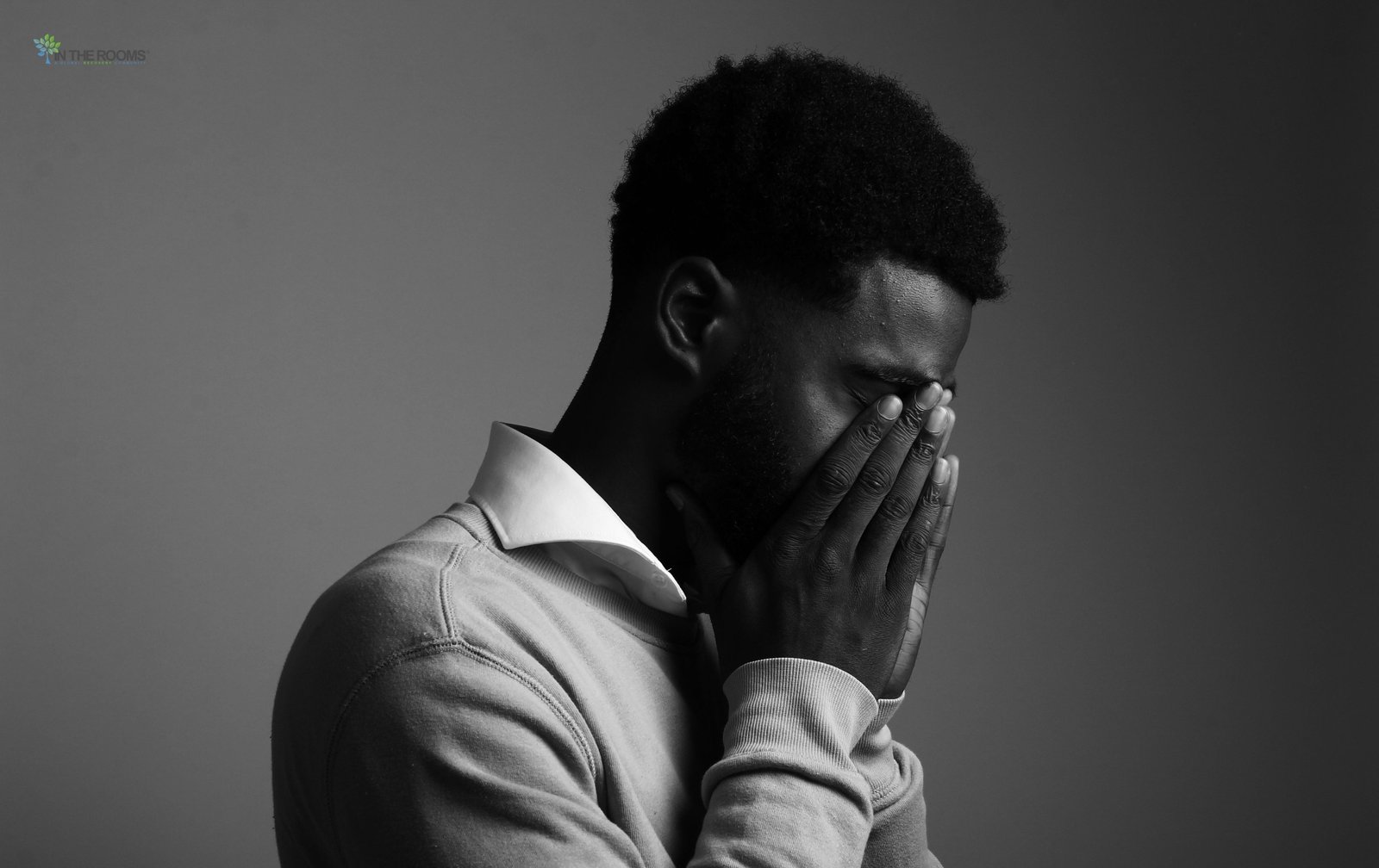 A man covering his face with his hands, expressing frustration, exhaustion, or emotional struggle during recovery.