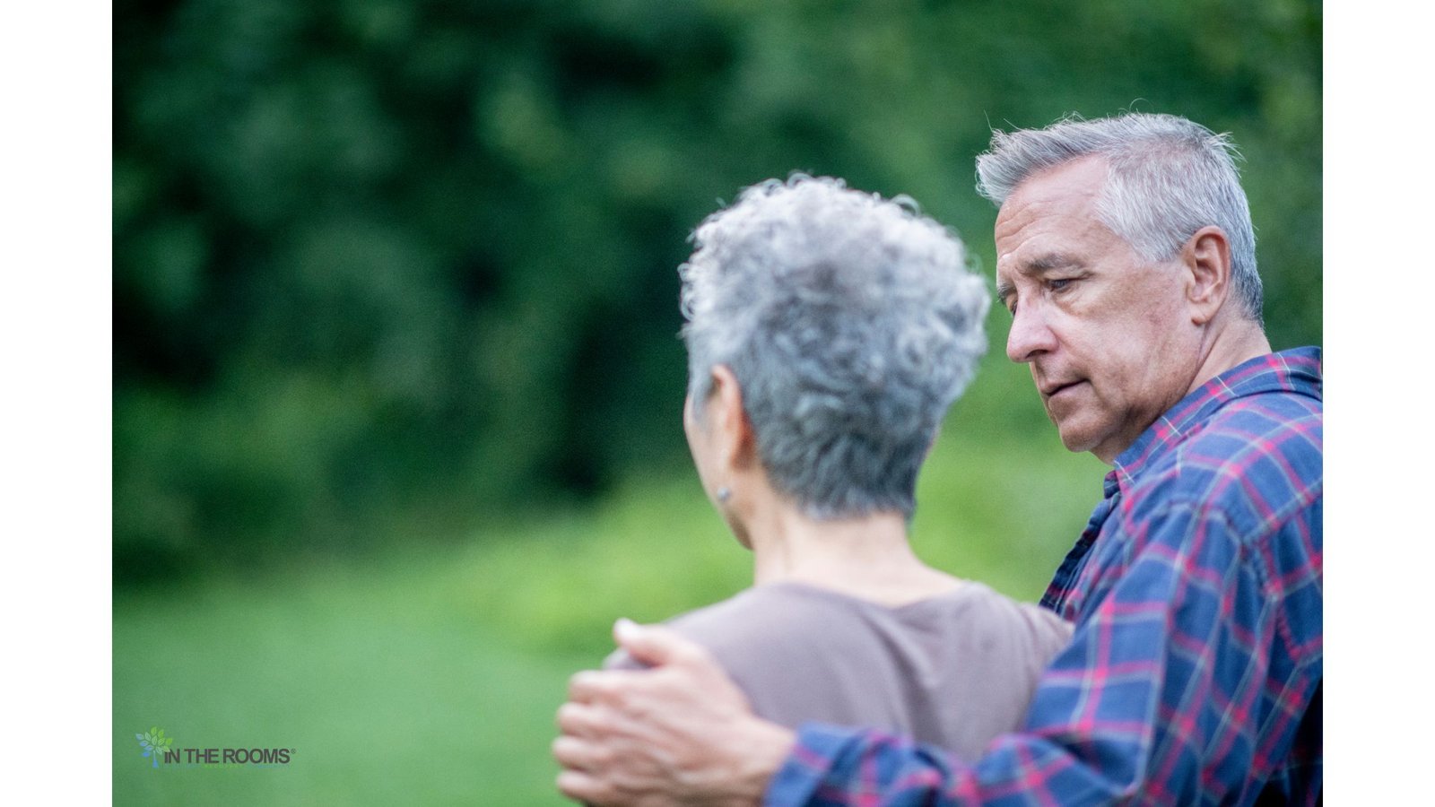 An older man comforts a loved one outdoors with a supportive arm around their shoulders, symbolizing compassion during the challenges of addiction recovery.