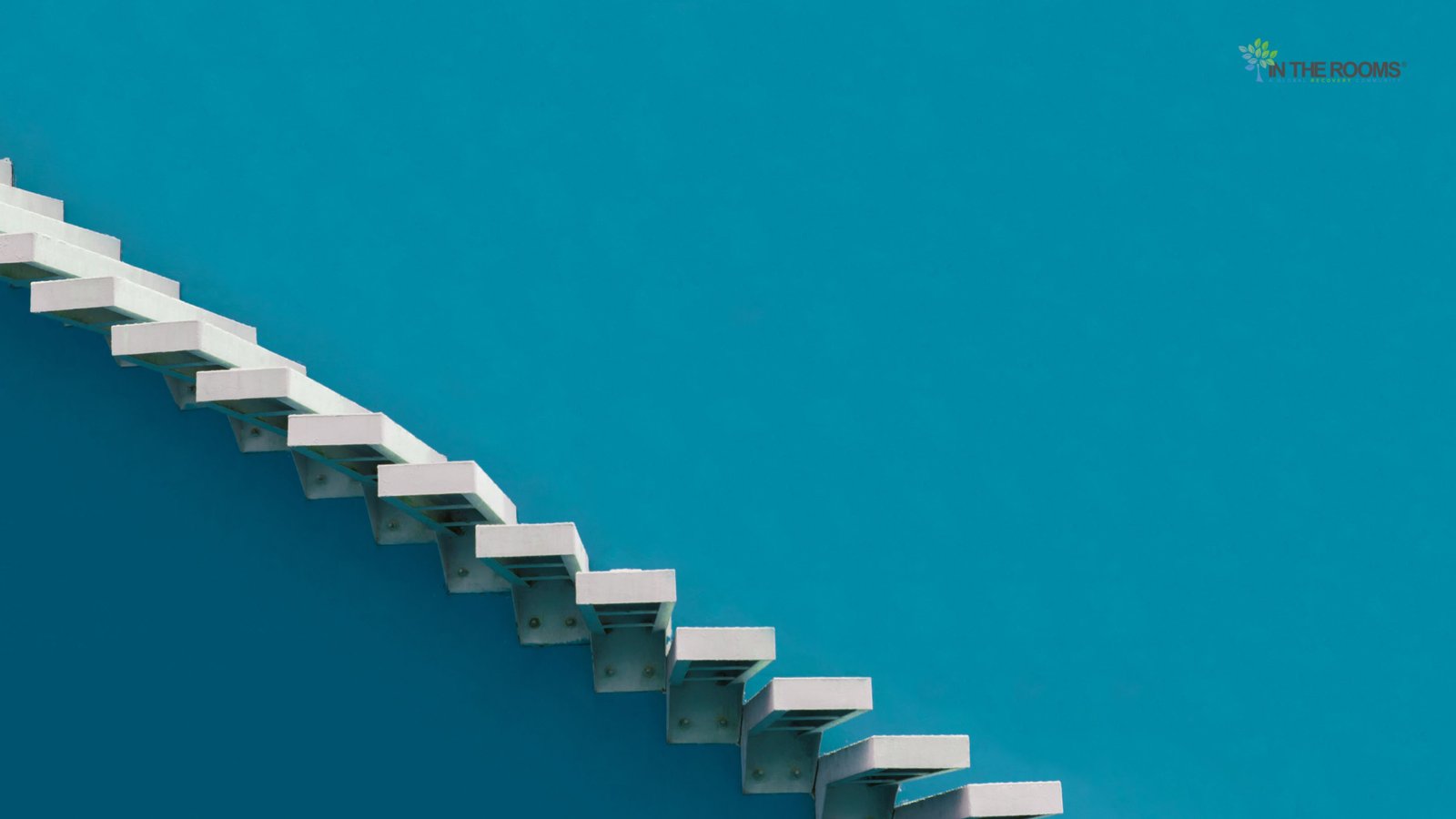 A minimalist staircase ascending against a bright blue sky, symbolizing progress and personal growth in recovery.