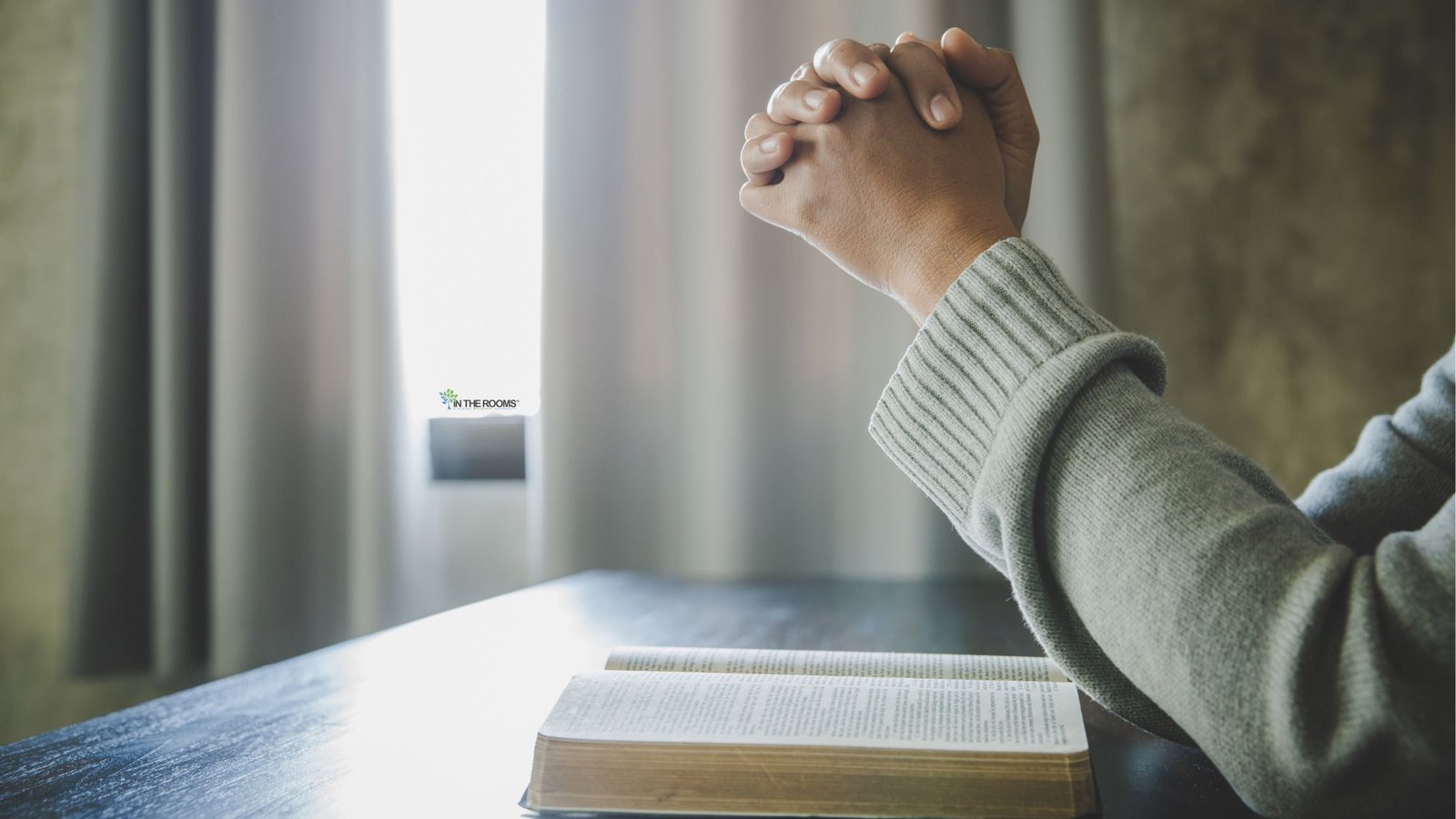 A person clasps their hands in prayer beside an open book, symbolizing spirituality, faith, hope, and inner strength during recovery.