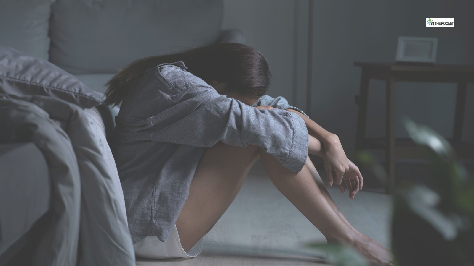 Person sitting on the floor with head resting on arms, representing feeling overwhelmed during recovery.