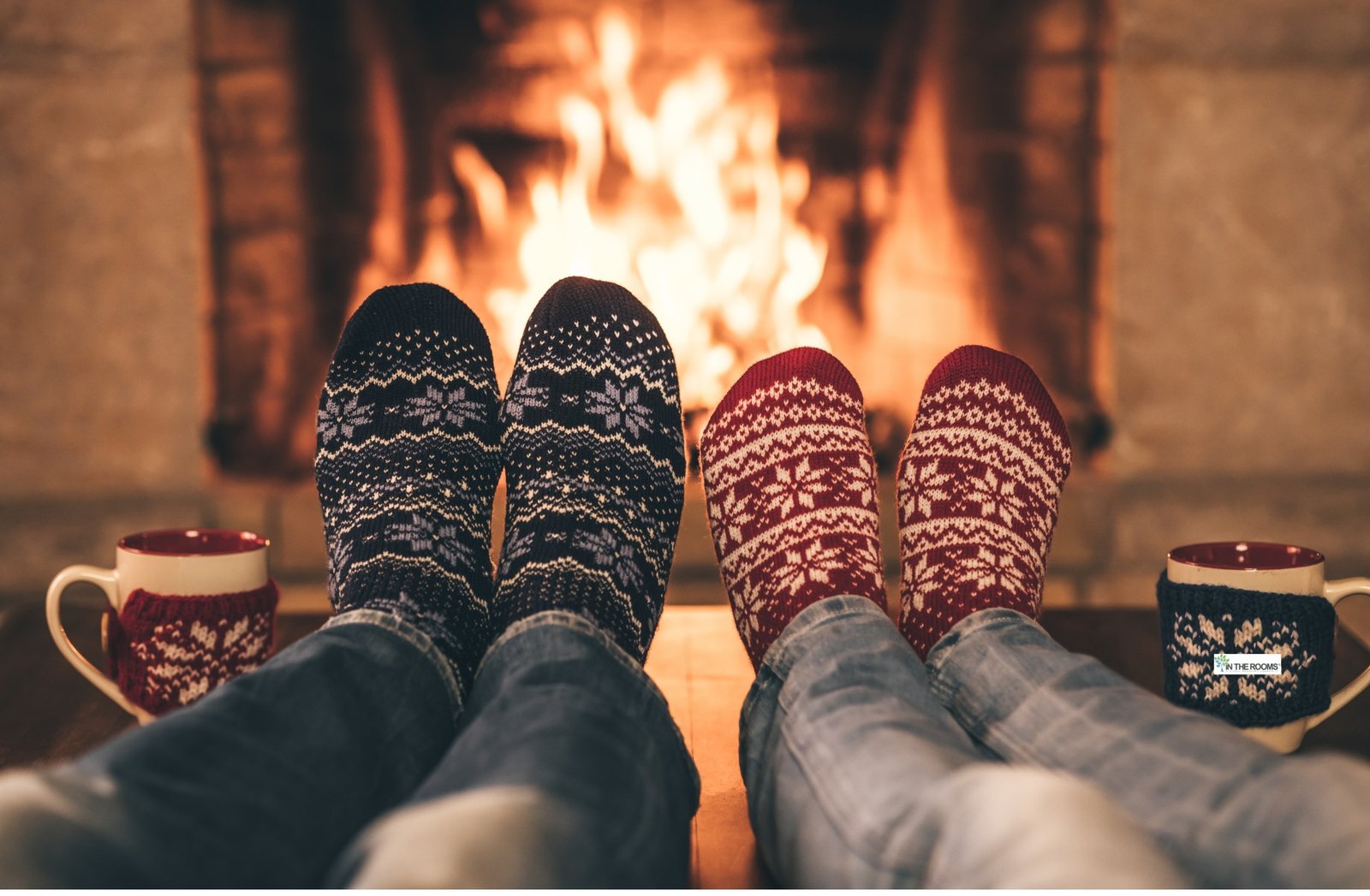 Two people in festive socks relaxing by a warm fireplace with mugs beside them, symbolizing calm, comfort, and a safe space during the holiday season.